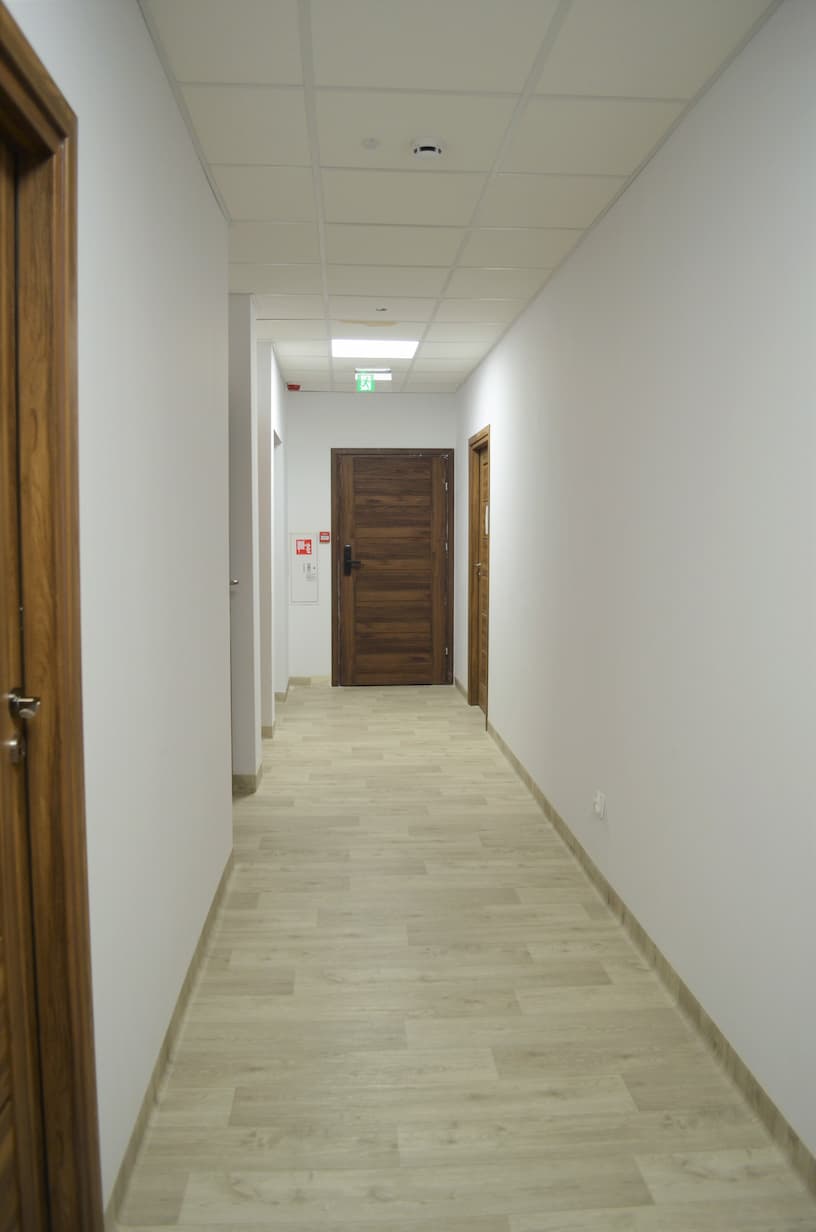 Biały korytarz z drewnianymi drzwiami